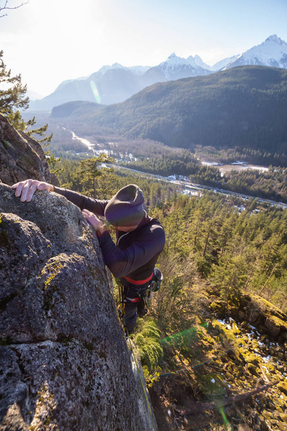 Male Rock climber climbing on the edge of the cliff during a sunny winter sunset. Taken in Area 44 near Squamish and Whistler, North of Vancouver, BC, Canada. - 写真・画像