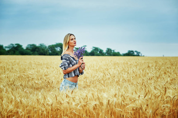 Jonge vrouw met een boeket van lavendel voor een wandeling in het veld - Foto, afbeelding