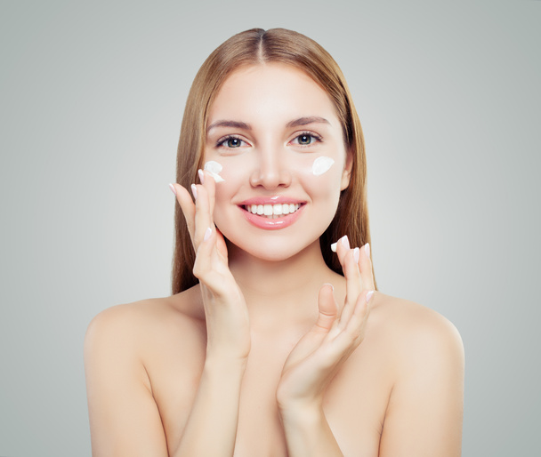 Young woman applying cream on healthy skin, spa portrait - Photo, Image