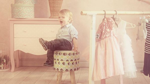 kaukázusi kisfiú ül a székre pózol a kamera otthon rózsaszín falak - Fotó, kép
