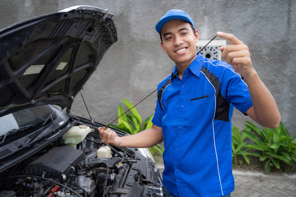 mécanicien avec uniforme inspection de l'huile de voiture
 - Photo, image