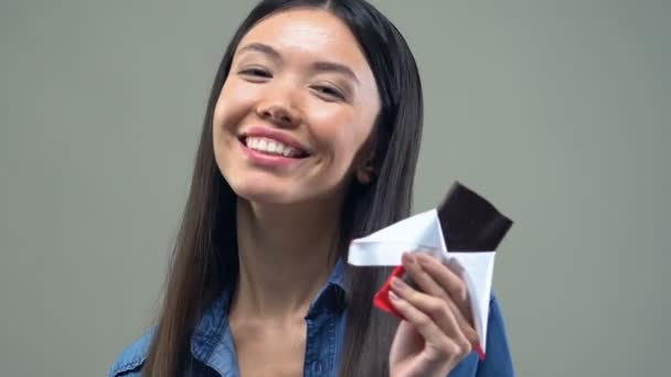 Smiling Asian woman eating chocolate bar, memory and mood improvement effect - Filmagem, Vídeo