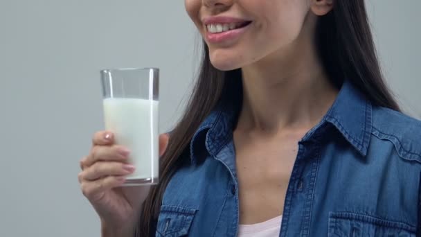 Cheerful woman drinking glass of milk, healthy beverage, essential nutrients - Πλάνα, βίντεο