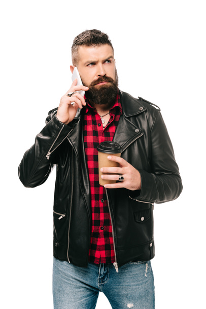 hombre barbudo en chaqueta de cuero negro sosteniendo café para ir y hablar en el teléfono inteligente, aislado en blanco
 - Foto, imagen