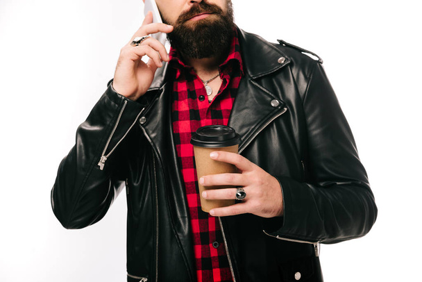 vista cortada do homem em jaqueta de couro preto segurando café para ir e falar no smartphone, isolado no branco
 - Foto, Imagem