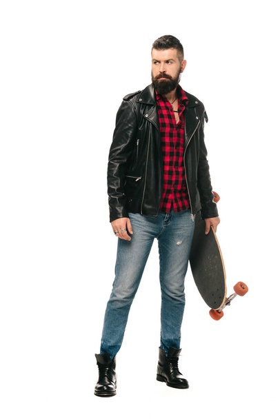 bearded skater in black leather jacket posing with longboard isolated on white - Foto, immagini
