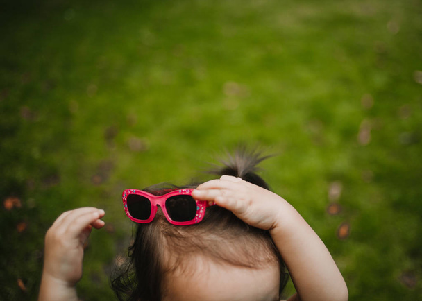 Chica tratando de gafas de sol fuera
 - Foto, Imagen