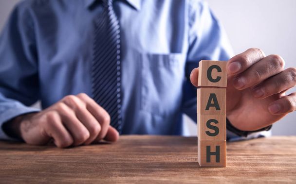 Man showing word Cash with wooden blocks. - Фото, изображение