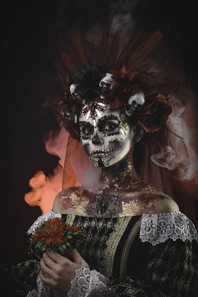 Santa Muerte Young Girl with Artistic Halloween Makeup and with Sculls in her Hair - Фото, изображение
