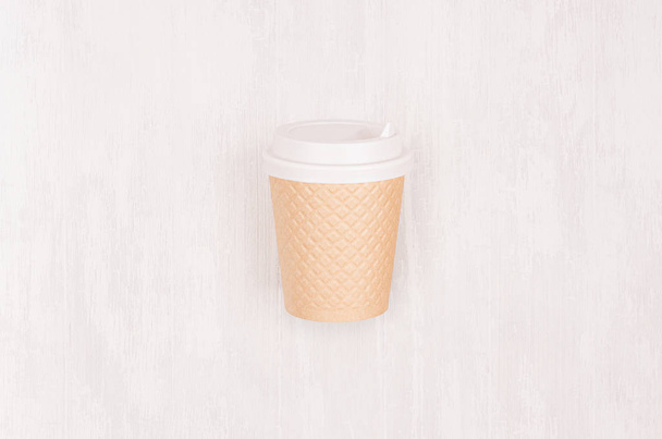Ribbed coffee kraft paper cup with white cap on light wood board, top view. Mockup for branding identity, advertising and design concept. - 写真・画像