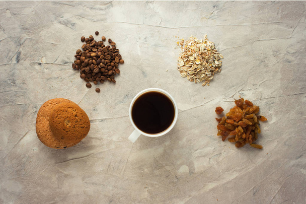 Cookies, flocons d'avoine, café, raisins secs et une tasse de café sur un fond clair. Concept de petit déjeuner
. - Photo, image