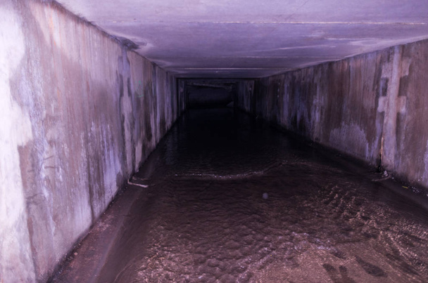 Een vierkante riool tunnel. Ondergrondse weg. Donkere weg en water. - Foto, afbeelding