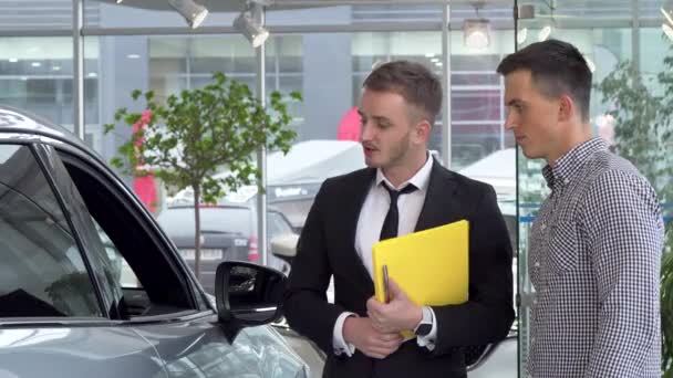 Friendly car dealer helping his male customer choosing automobile to buy - Footage, Video
