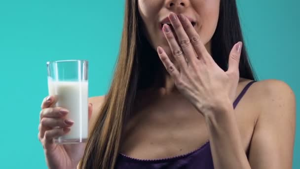 Smiling lady in pajamas drinking glass of milk in the morning, healthy sleep - Filmati, video