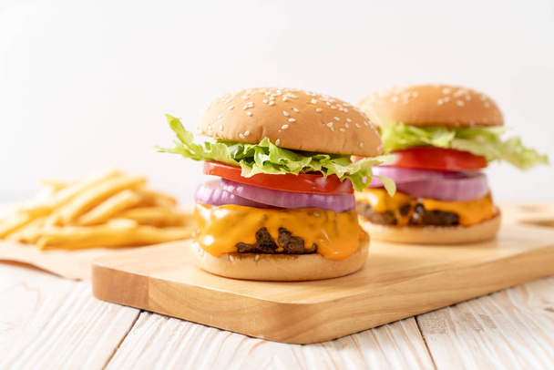 fresh tasty beef burger with cheese and french fries on wood background - Фото, изображение
