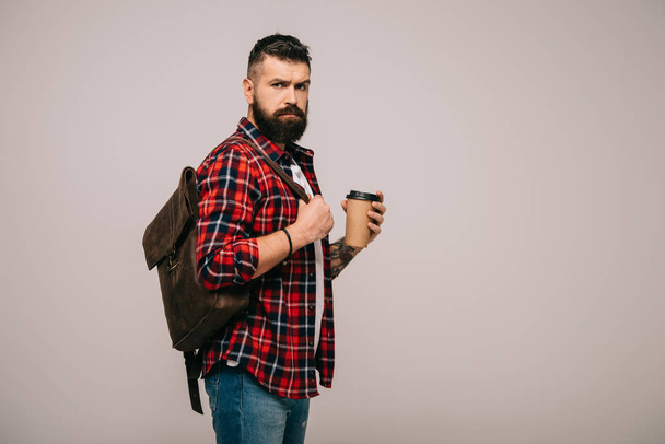 serious handsome man in checkered shirt holding paper cup of coffee isolated on grey - Foto, Imagen
