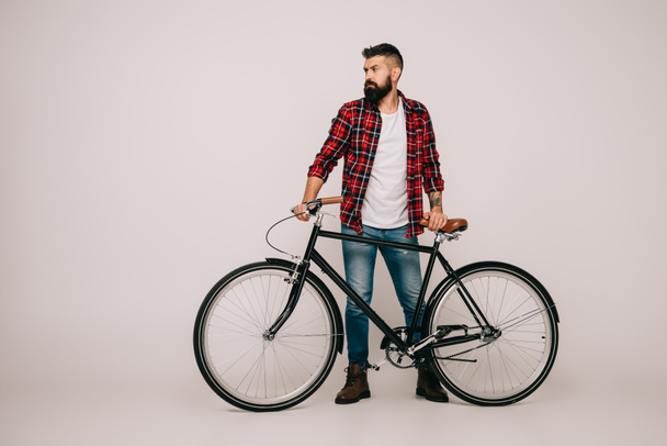 hombre barbudo con camisa a cuadros posando con bicicleta en gris
 - Foto, Imagen