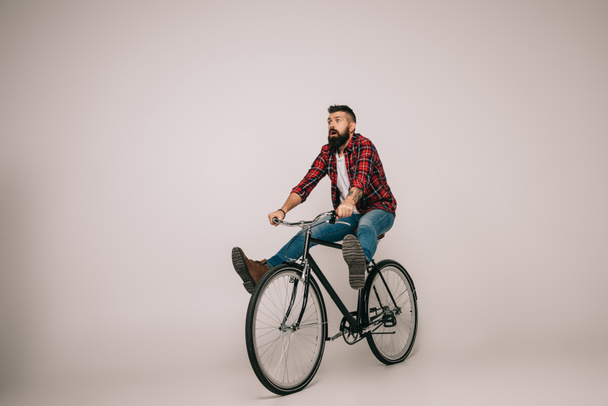 bearded excited man riding bike isolated on grey - Photo, Image