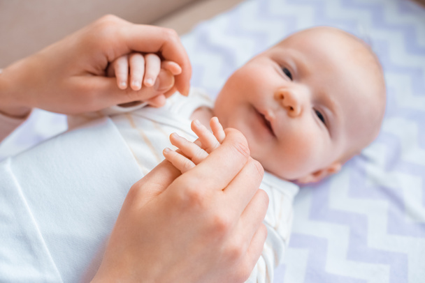 cropped shot of mother holding hands of adorable infant baby looking at camera - Foto, Imagen