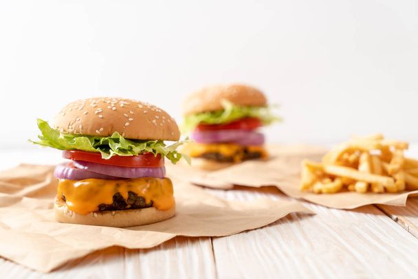 fresh tasty beef burger with cheese and french fries on wood background - Photo, image