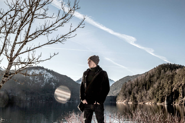 handsome young man standing near lake in winter mountains - Fotografie, Obrázek