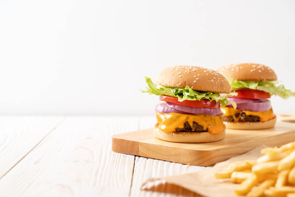 fresh tasty beef burger with cheese and french fries on wood background - Zdjęcie, obraz