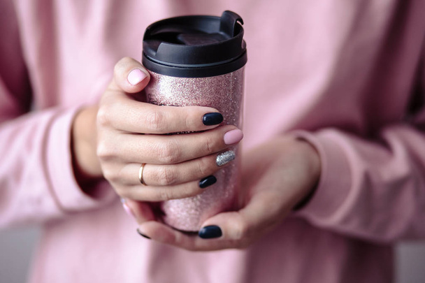 Gorgeous manicure, pastel tender pink color nail polish, closeup photo. Female hands hold a plastic coffee cup over simple background - Foto, immagini