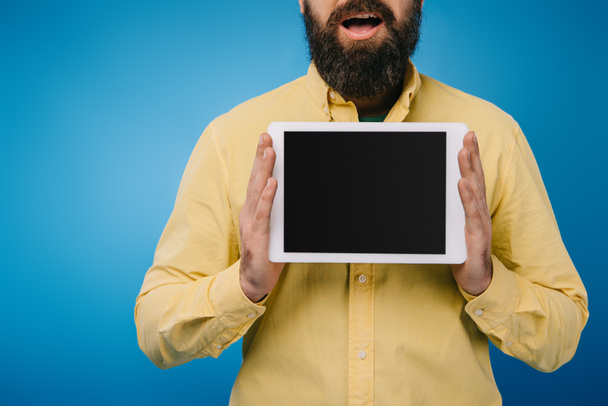 cropped view of excited man showing digital tablet with blank screen, isolated on blue - 写真・画像