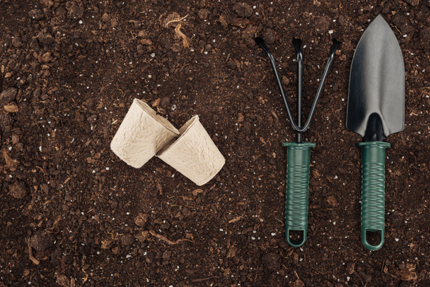 top view of used paper cups near rake and shovel on ground, protecting nature concept  - Photo, Image