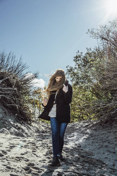 girl with long hair in a warm jacket, walking along the beach of the cold Baltic Sea - Foto, imagen