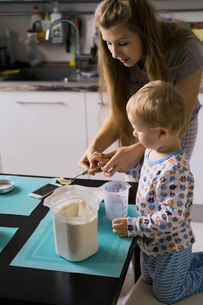 boy child in pajamas in the morning with mom cooking apple pie in the kitchen and playing with toys - Fotoğraf, Görsel