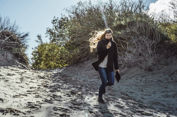girl with long hair in a warm jacket, walking along the beach of the cold Baltic Sea - Φωτογραφία, εικόνα