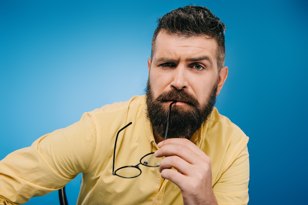 подозрительный бородатый мужчина в очках, изолированных на синий
 - Фото, изображение
