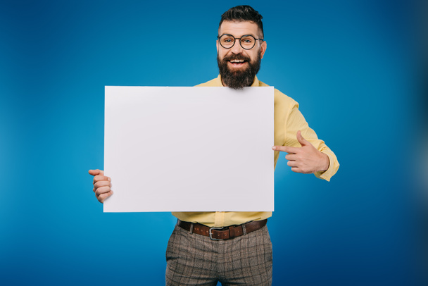 cheerful bearded man pointing at empty board isolated on blue - Fotoğraf, Görsel