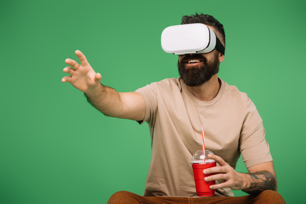smiling man with soda using Vr headset isolated on green - Zdjęcie, obraz
