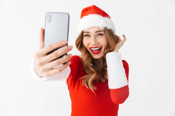 Image of a beautiful emotional woman in christmas costume take a selfie by mobile phone. - Foto, Bild