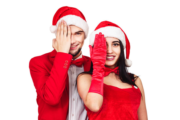 クリスマス テーマ パーティーでの楽しみを持っている若いカップル。サンタの帽子と赤いスーツを着た女性、若い男。白で隔離 - 写真・画像