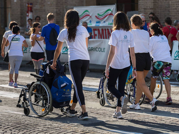 Disabled Athlete in a Sport Wheelchair during Marathon Helped by Female Runners. - Photo, Image
