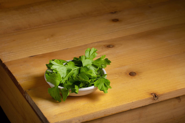 Parsley in a bowl on a wooden table - Photo, Image