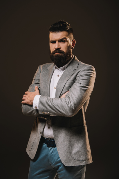handsome businessman posing with crossed arms isolated on brown - Фото, зображення