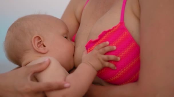 Vrouw voeding baby op strand. De pasgeboren kind van de moeder borstvoeding op handen - Video