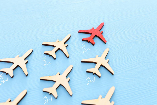 Leadership concept with airplanes on blue wooden background. One red leader flays ahead others. - Foto, imagen