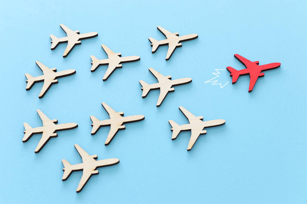 Leadership concept with airplanes on blue wooden background. One red leader flays ahead others. - Photo, Image