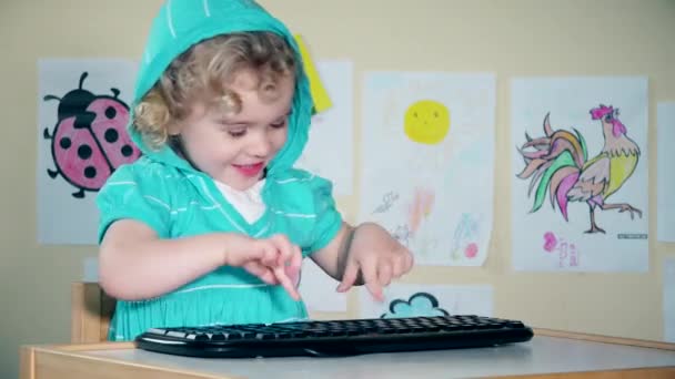Hravá roztomilá holčička hrát s klávesnicí počítače a při pohledu na fotoaparát - Záběry, video
