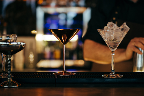 enfoque selectivo de cócteles alcohólicos en el mostrador con barman en el fondo
 - Foto, imagen