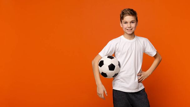 オレンジ スタジオの背景にはサッカー ボールでポーズの少年 - 写真・画像