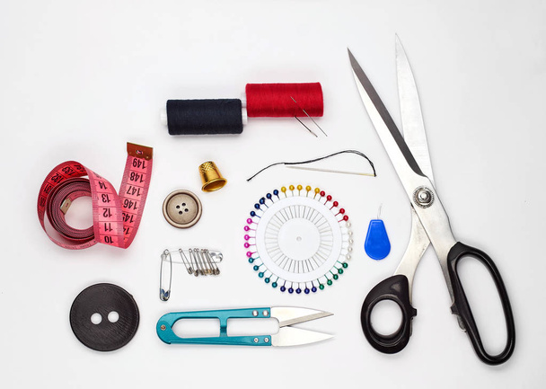 Sewing supplies and accessories for needlework. Fabric, spools of thread, scissors and thimbles on white background. - Fotografie, Obrázek