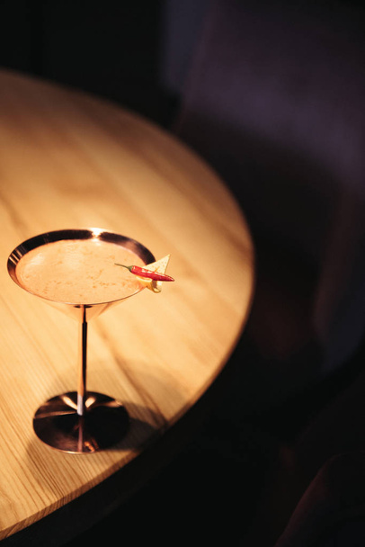 alcoholic cocktail in metal glass decorated with chili pepper and nacho chip on wooden table - 写真・画像