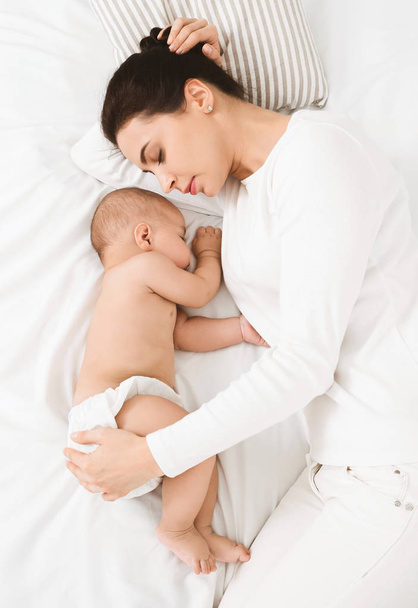 Mladá maminka a její roztomilé dítě spí v posteli - Fotografie, Obrázek