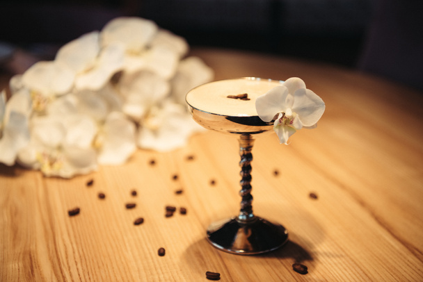selective focus of alcoholic cocktail in metal glass decorated with orchid flower on wooden table - Photo, Image